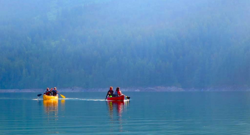 two canoes are paddled by outward bound students on calm blue water